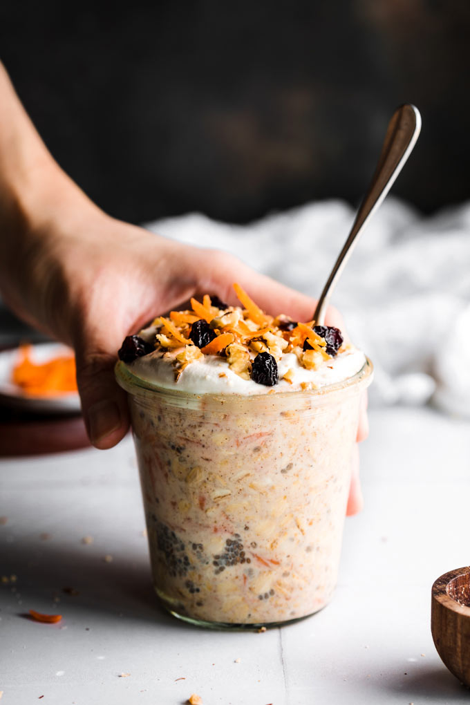 Carrot Cake Overnight Oats - with one hand holding the jar